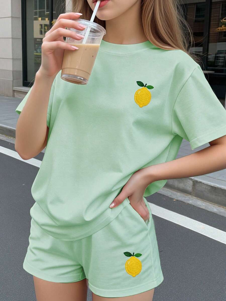 Tween girls two-piece green summer outfit featuring a fruit print short sleeve round neck t-shirt and matching track shorts with pockets.