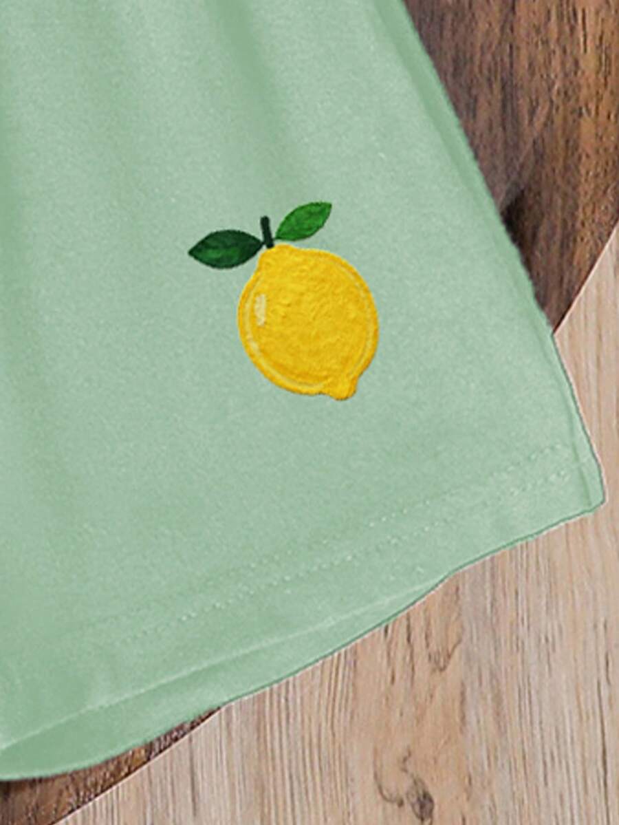 Tween girls two-piece green summer outfit featuring a fruit print short sleeve round neck t-shirt and matching track shorts with pockets.