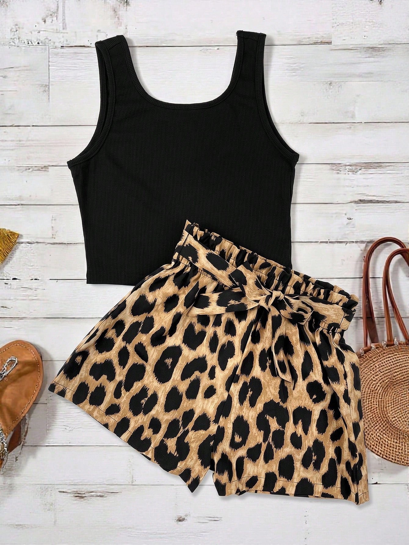 Tween girl wearing a casual 2-piece set featuring a black rib-knit scoop neck tank top and leopard print paperbag waist shorts with a matching belt.