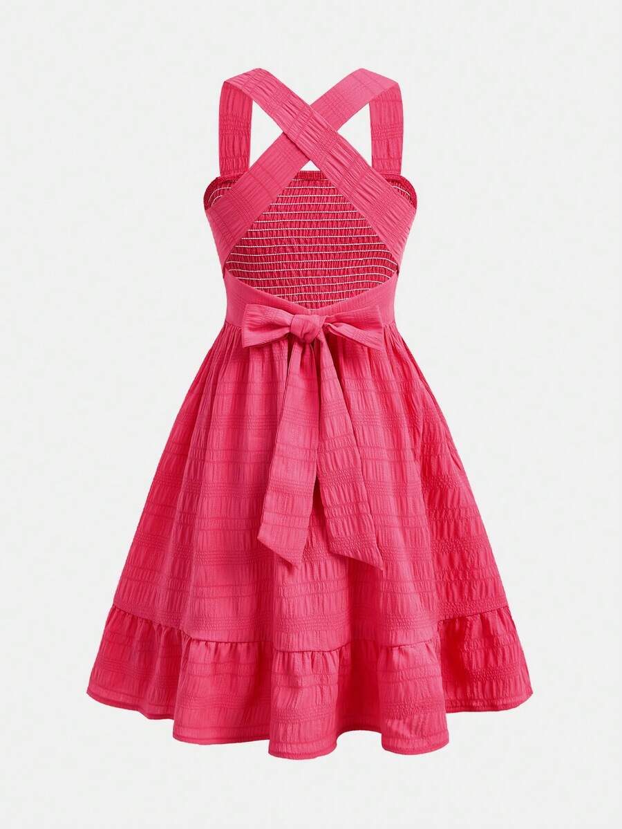 Pink sleeveless tween girls vacation dress with all-over fruit and vegetable print, strap neckline, belted high waist, cut-out detail, and flared ruffle hem.