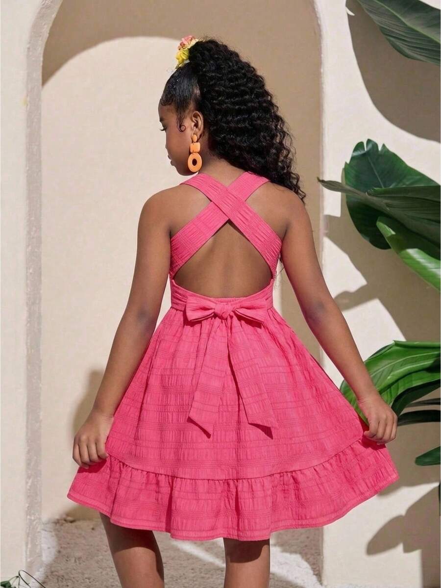 Pink sleeveless tween girls vacation dress with all-over fruit and vegetable print, strap neckline, belted high waist, cut-out detail, and flared ruffle hem.