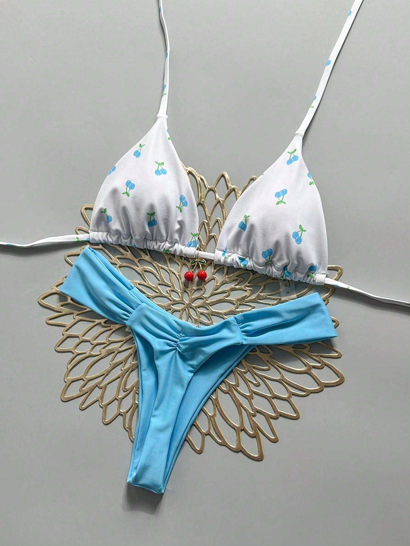 Women's 2-piece triangle cup bikini set in solid color featuring woven pearl shell decoration, halter neckline, and high-waist side-tie ruched bottoms.