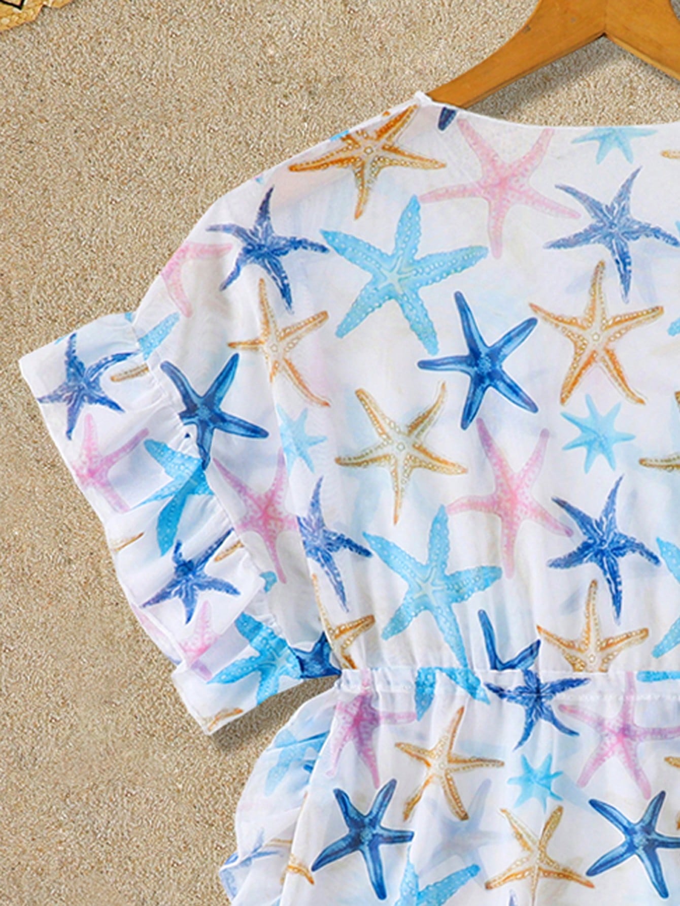 Blue tween girls swimsuit cover up with geometric starfish print, ruffle trim, round neck, short sleeves, and semi-sheer knit fabric for beach or pool wear.