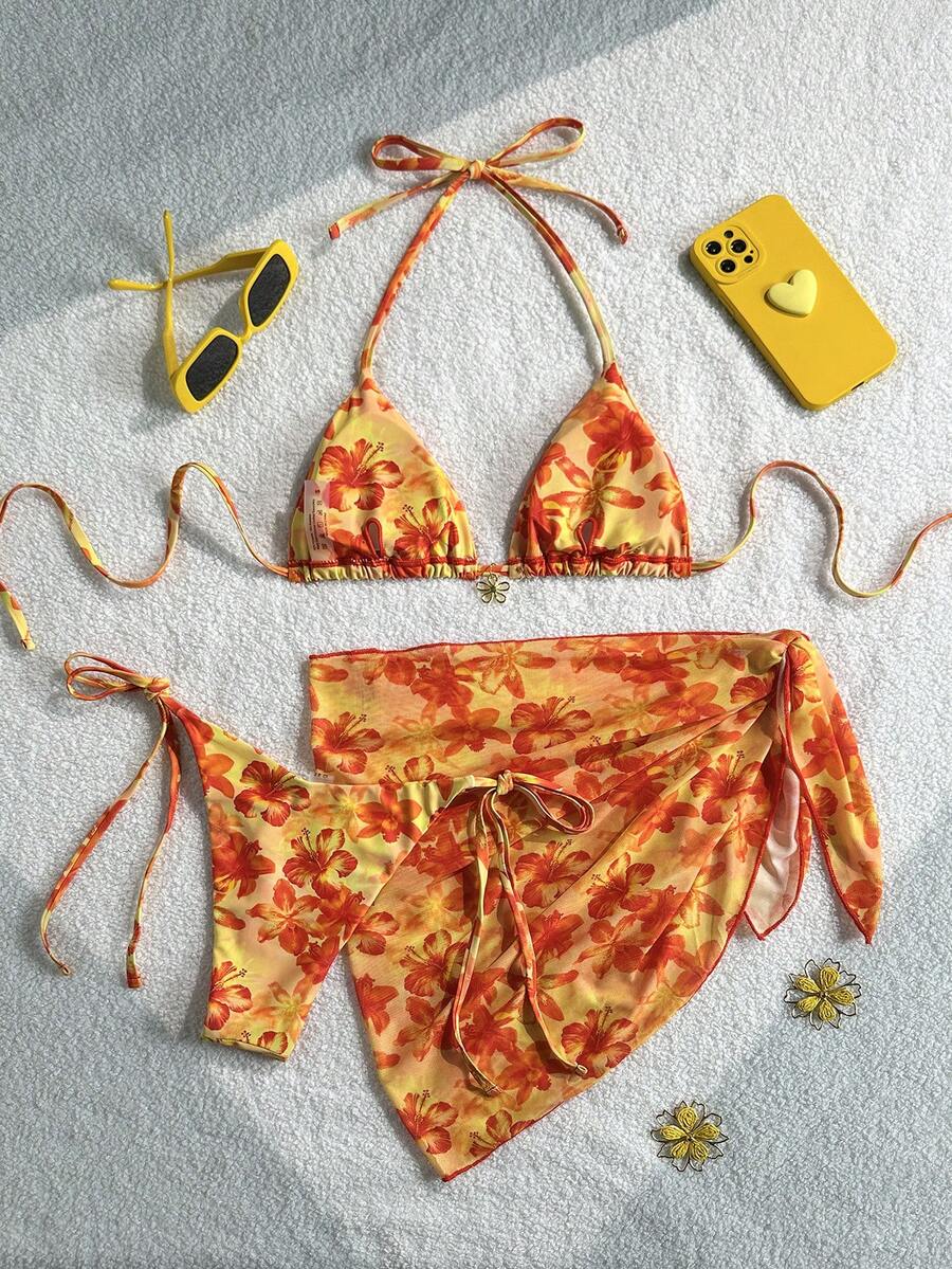 Women's 3-piece blue tropical shell print bikini set featuring a halter bralette top, low-waist tie-side bottom, and a matching sheer mesh cover-up skirt.