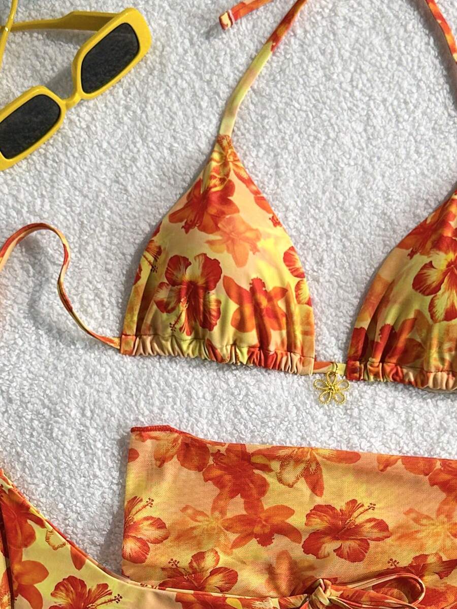 Women's 3-piece blue tropical shell print bikini set featuring a halter bralette top, low-waist tie-side bottom, and a matching sheer mesh cover-up skirt.