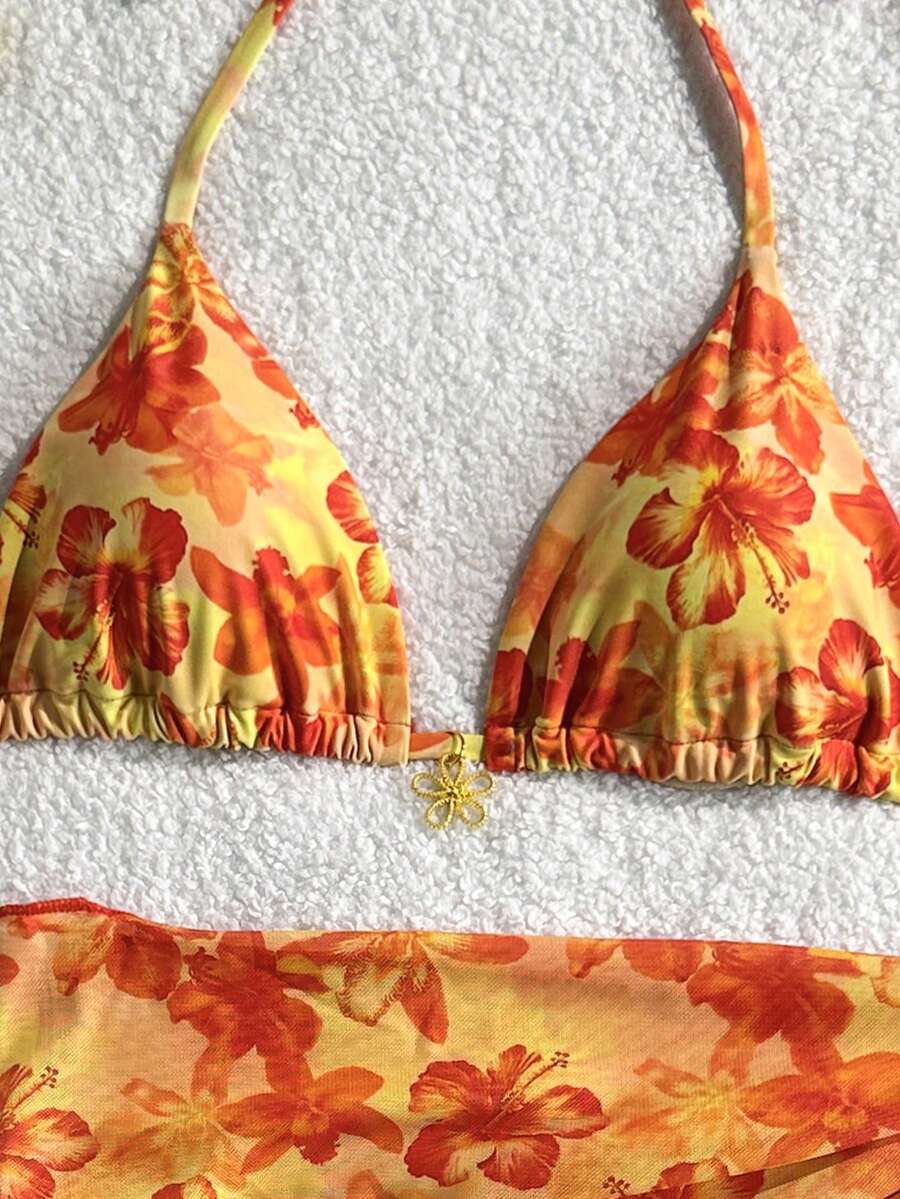 Women's 3-piece blue tropical shell print bikini set featuring a halter bralette top, low-waist tie-side bottom, and a matching sheer mesh cover-up skirt.