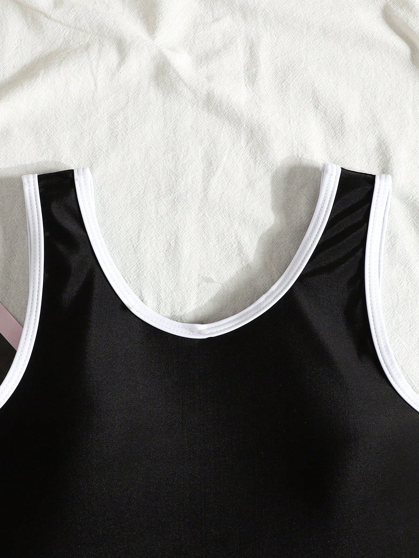Tween girls' black and white one-piece swimsuit with striped patchwork design, scoop neck, asymmetrical cut-out detail, and fitted vacation swimwear style.