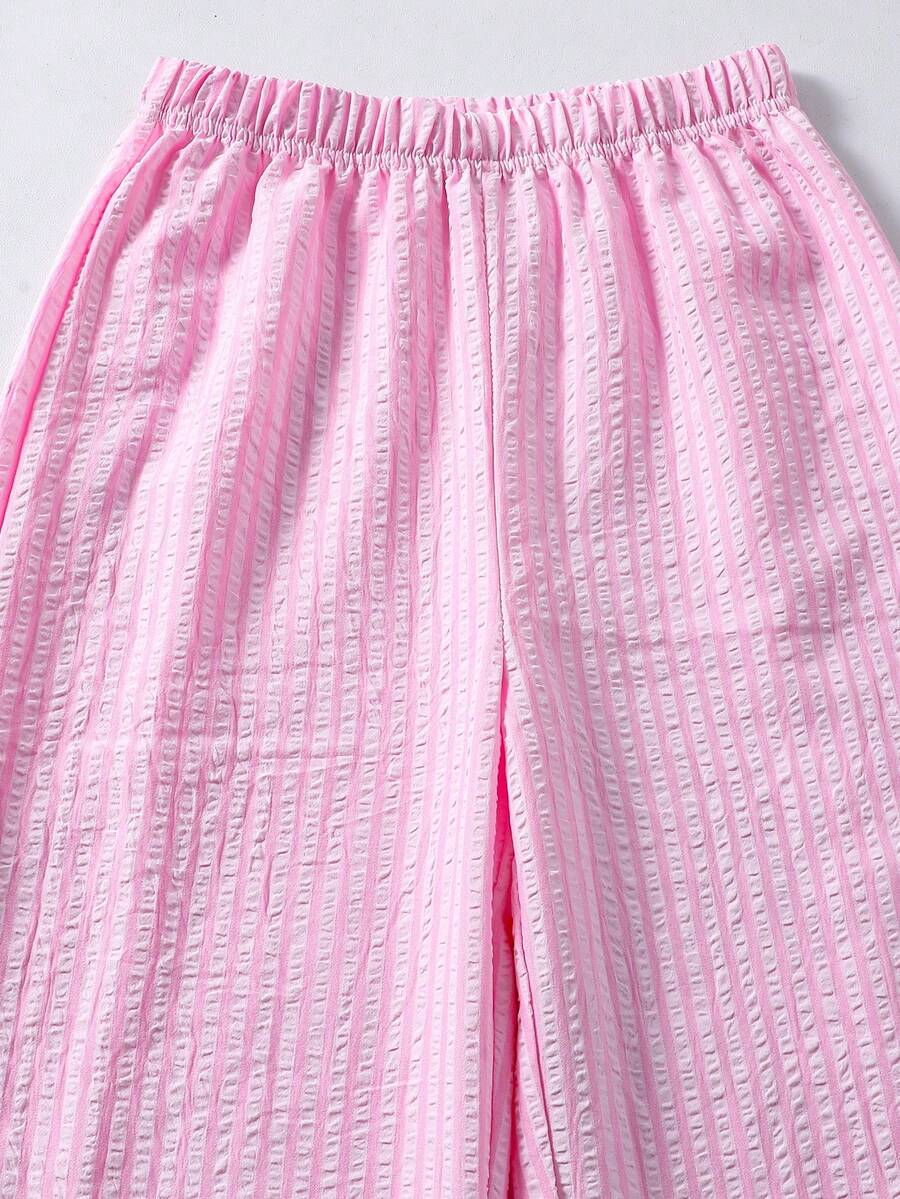Tween girl wearing an apricot 2-piece outfit set featuring a shirred spaghetti strap short cami top and matching wide-leg long pants.