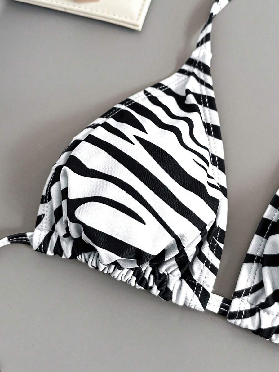 Women's black and white zebra print two-piece bikini set featuring a high waist tie-side bottom and a backless halter top with removable padding.