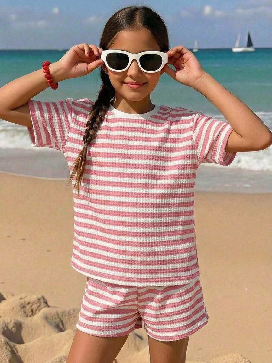 Tween girl wearing a black and white striped drop-shoulder crew neck t-shirt with bow embroidery paired with matching tie-waist shorts.