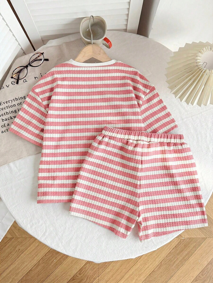 Tween girl wearing a black and white striped drop-shoulder crew neck t-shirt with bow embroidery paired with matching tie-waist shorts.