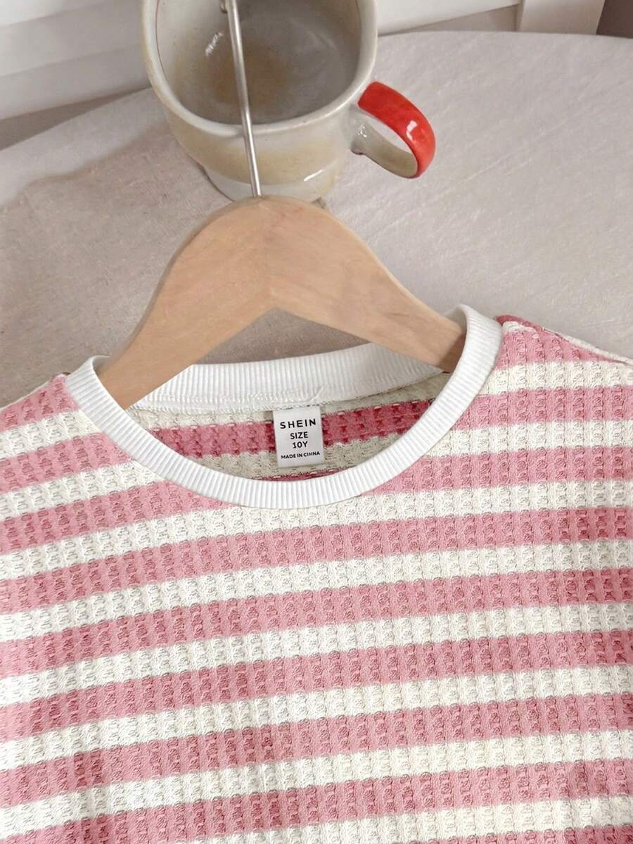 Tween girl wearing a black and white striped drop-shoulder crew neck t-shirt with bow embroidery paired with matching tie-waist shorts.