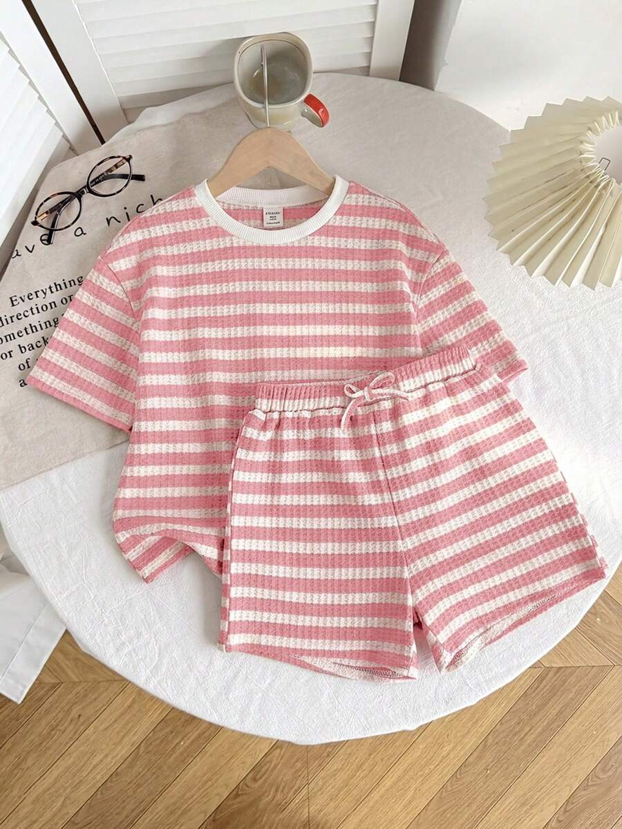 Tween girl wearing a black and white striped drop-shoulder crew neck t-shirt with bow embroidery paired with matching tie-waist shorts.