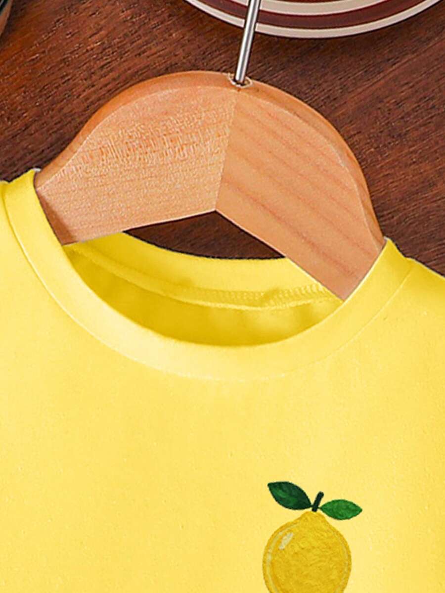 Tween girls two-piece green summer outfit featuring a fruit print short sleeve round neck t-shirt and matching track shorts with pockets.