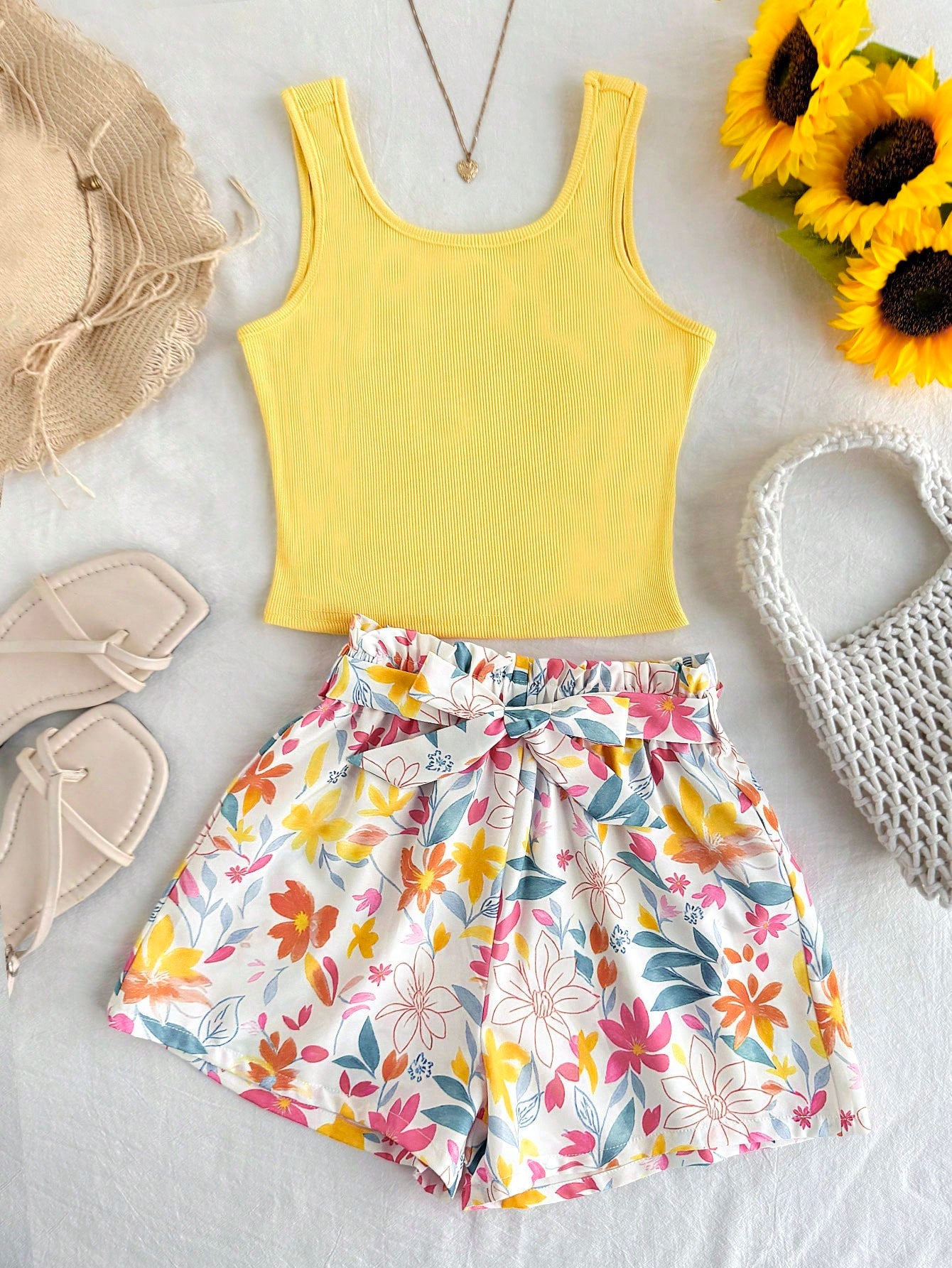 Tween girl wearing a casual 2-piece set featuring a black rib-knit scoop neck tank top and leopard print paperbag waist shorts with a matching belt.