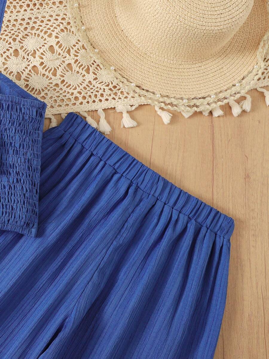 Tween girl wearing a black sleeveless spaghetti strap camisole top with 3D bow decor and matching leopard print wide leg long pants.