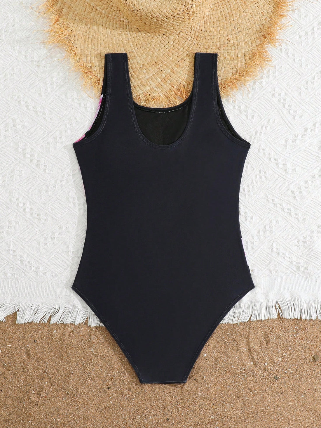 Tween girls one-piece swimsuit with a black base and multicolor tropical plant print featuring bamboo, palm leaves, plumeria flowers, scoop neck, and wide straps.