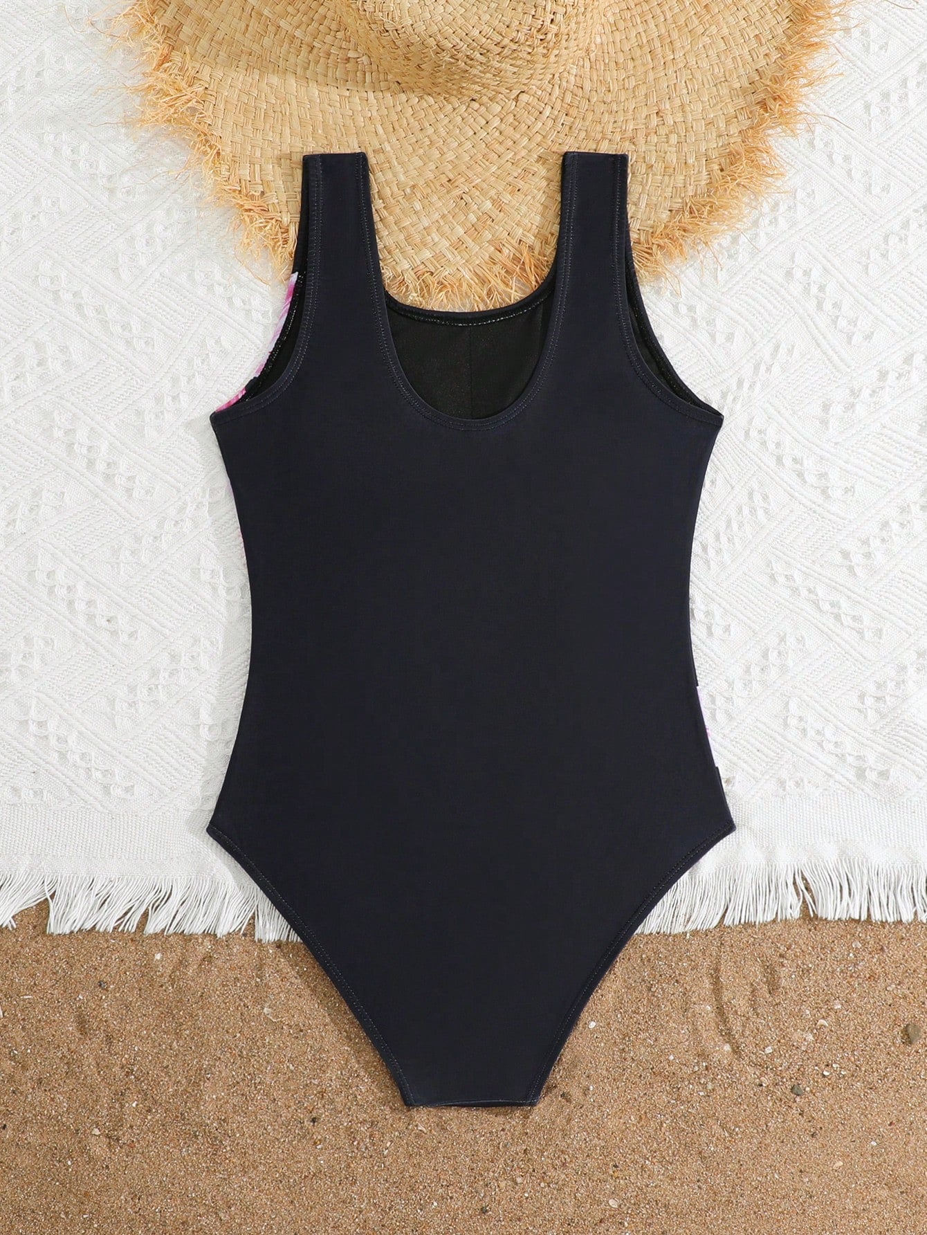 Tween girls one-piece swimsuit with a black base and multicolor tropical plant print featuring bamboo, palm leaves, plumeria flowers, scoop neck, and wide straps.