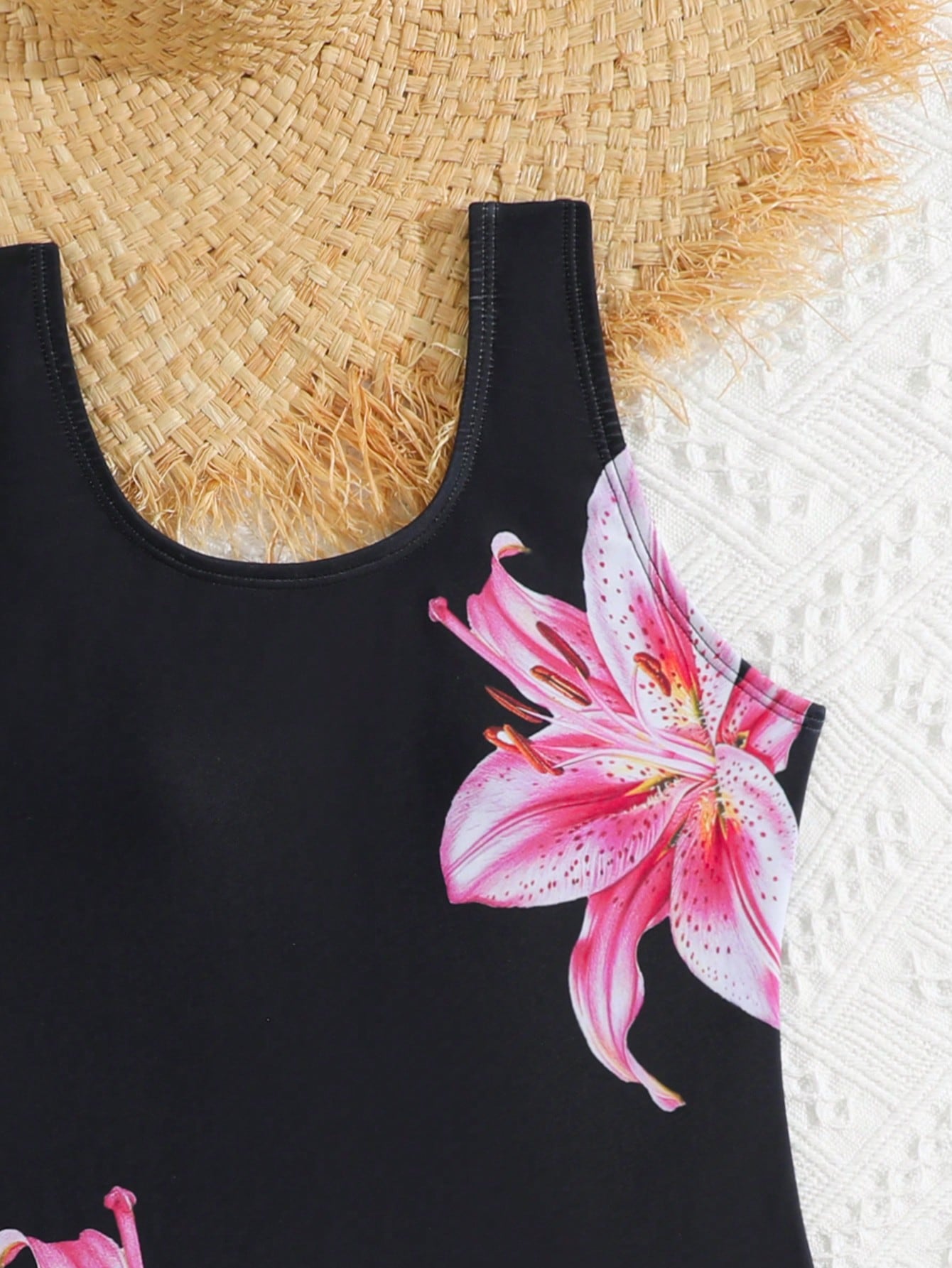 Tween girls one-piece swimsuit with a black base and multicolor tropical plant print featuring bamboo, palm leaves, plumeria flowers, scoop neck, and wide straps.