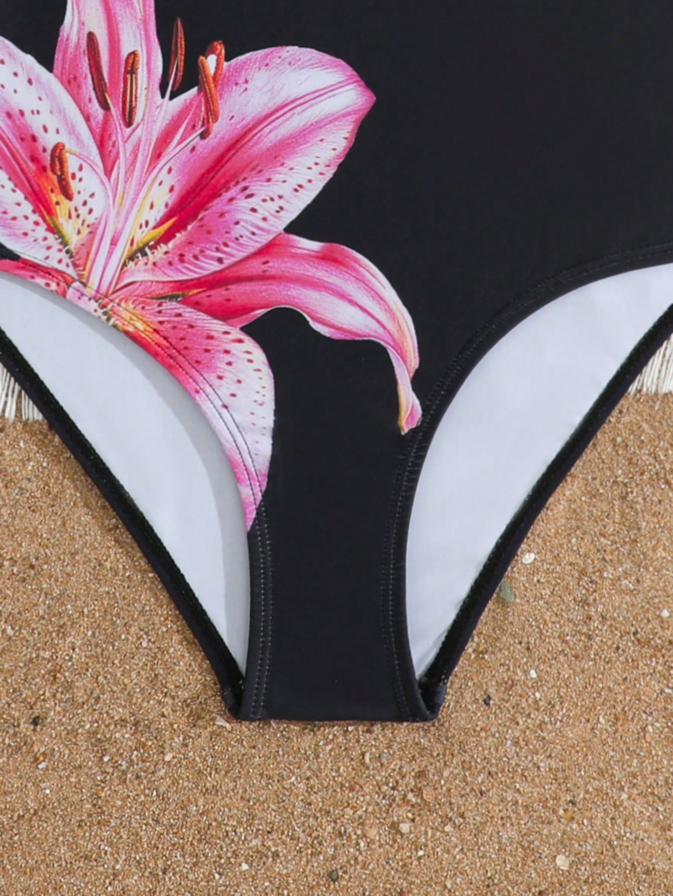 Tween girls one-piece swimsuit with a black base and multicolor tropical plant print featuring bamboo, palm leaves, plumeria flowers, scoop neck, and wide straps.