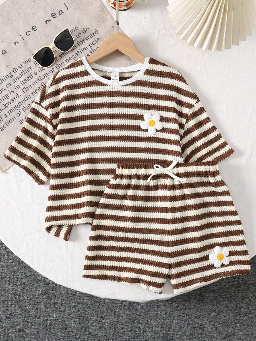 Tween girl wearing a black and white striped drop-shoulder crew neck t-shirt with bow embroidery paired with matching tie-waist shorts.