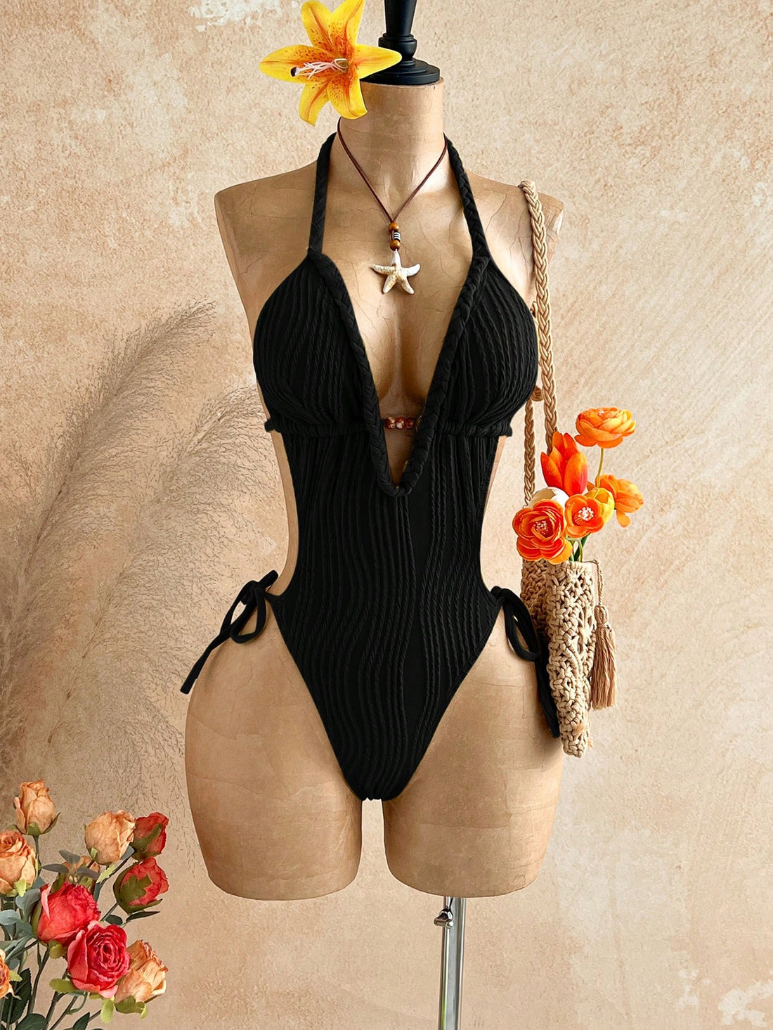Black halter one-piece swimsuit for women featuring a twist open back, cutout detailing, wireless bra with removable padding, and high cut tie side bottoms.