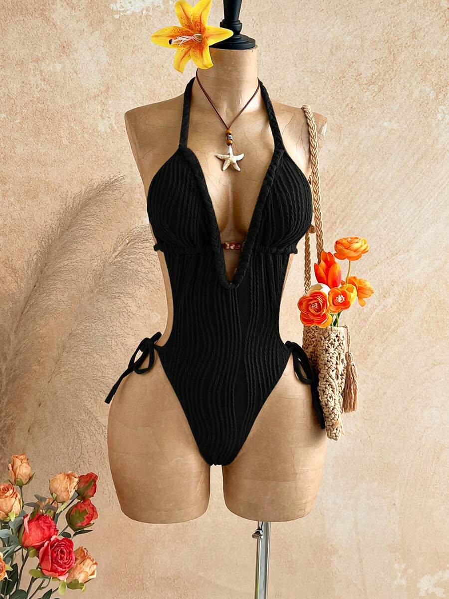Black halter one-piece swimsuit for women featuring a twist open back, cutout detailing, wireless bra with removable padding, and high cut tie side bottoms.