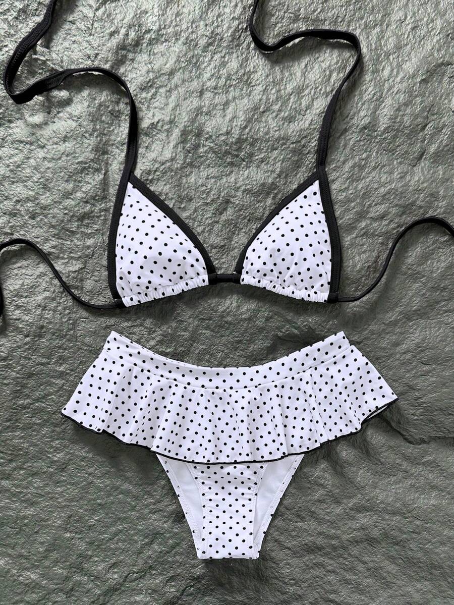 Women's 70s retro black and white polka dot bikini set featuring a halter triangle top and ultra low waist bottoms.