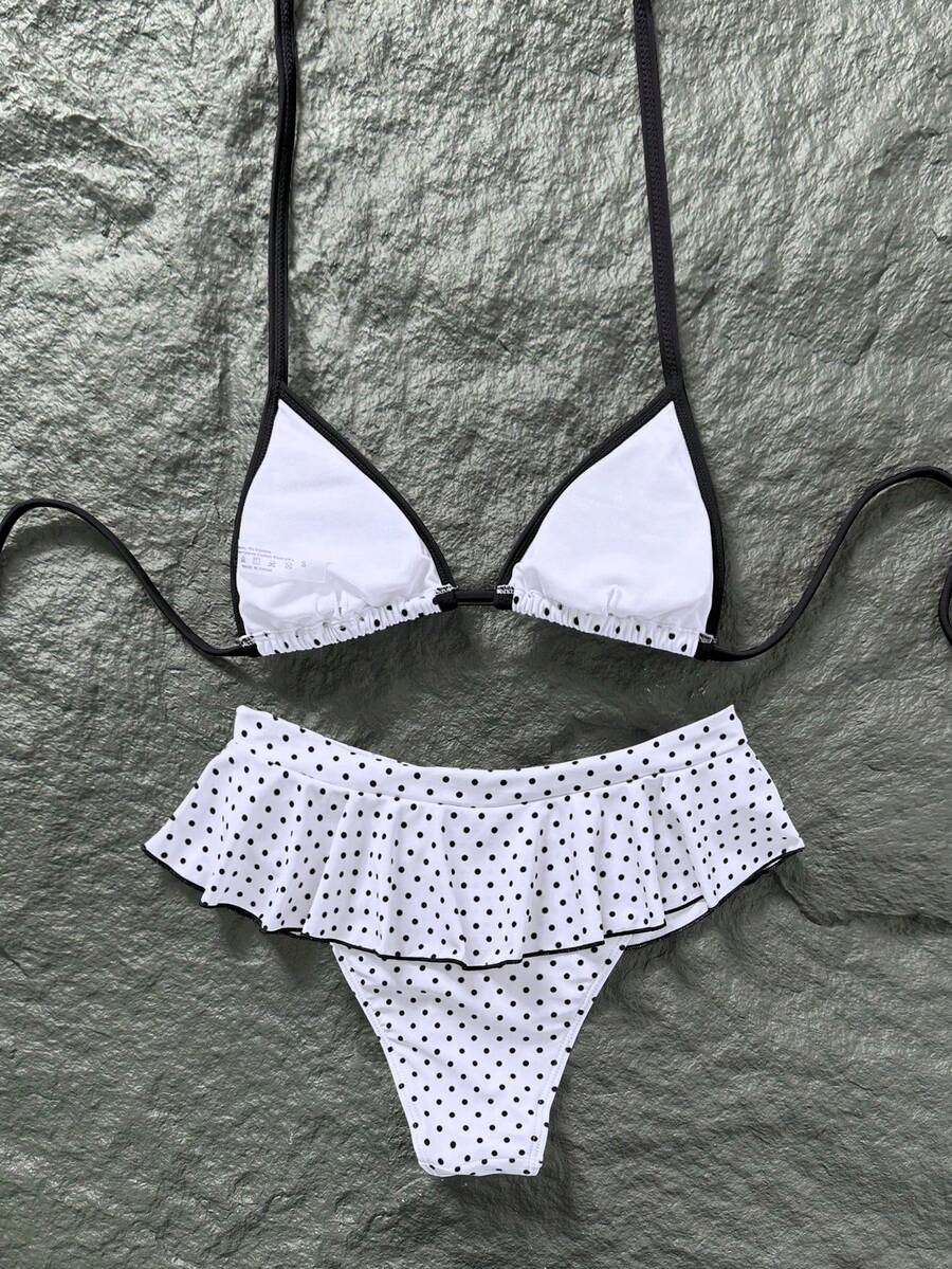 Women's 70s retro black and white polka dot bikini set featuring a halter triangle top and ultra low waist bottoms.