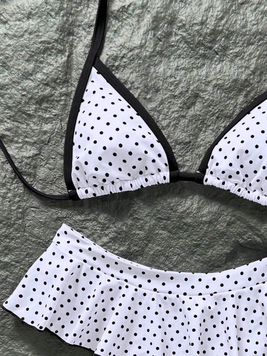 Women's 70s retro black and white polka dot bikini set featuring a halter triangle top and ultra low waist bottoms.