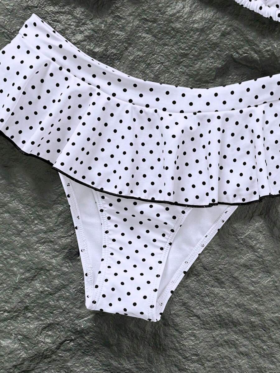 Women's 70s retro black and white polka dot bikini set featuring a halter triangle top and ultra low waist bottoms.