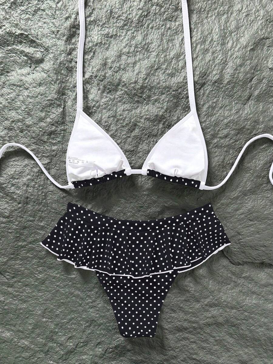 Women's 70s retro black and white polka dot bikini set featuring a halter triangle top and ultra low waist bottoms.