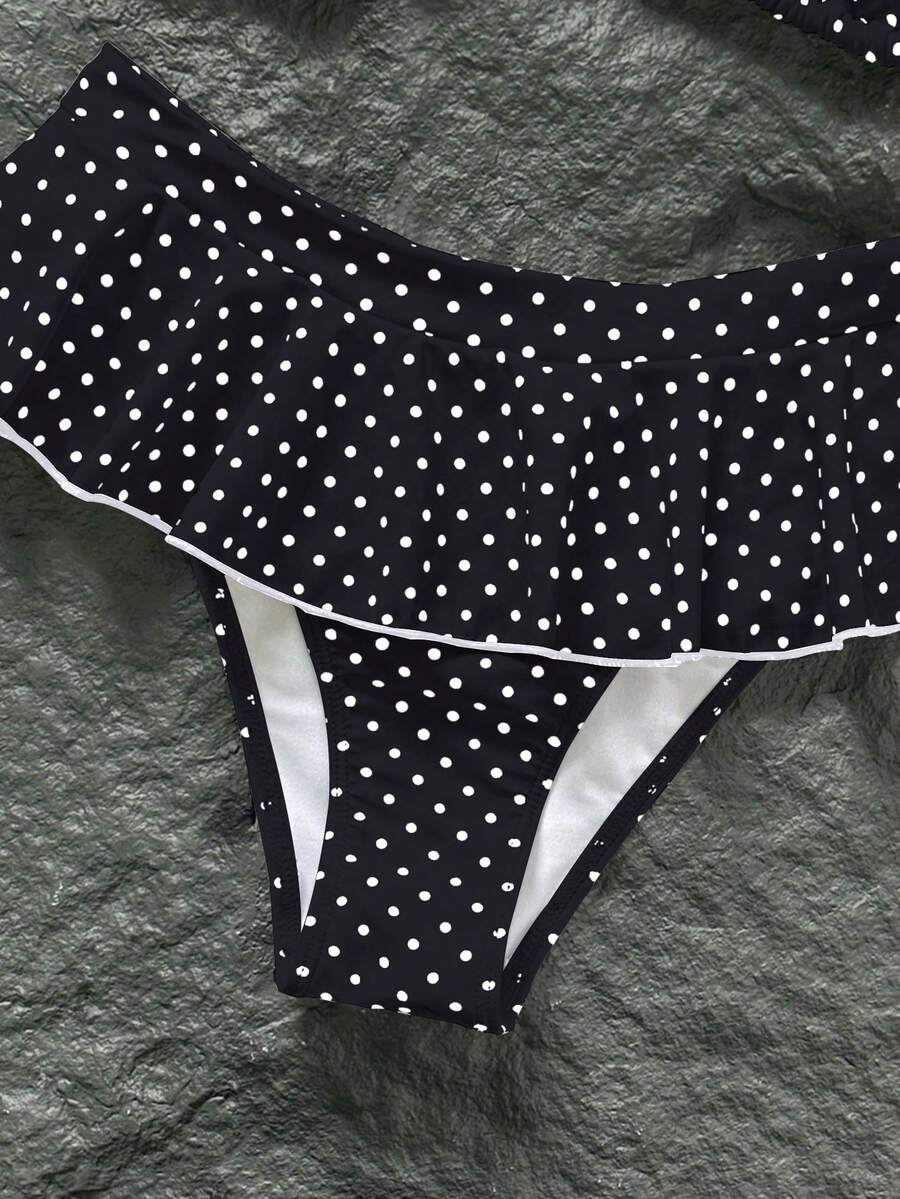 Women's 70s retro black and white polka dot bikini set featuring a halter triangle top and ultra low waist bottoms.