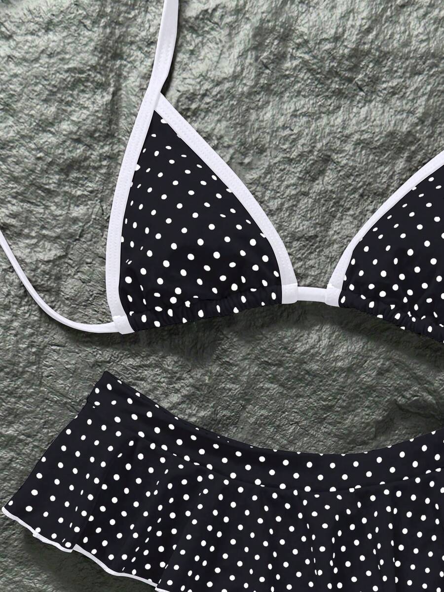Women's 70s retro black and white polka dot bikini set featuring a halter triangle top and ultra low waist bottoms.
