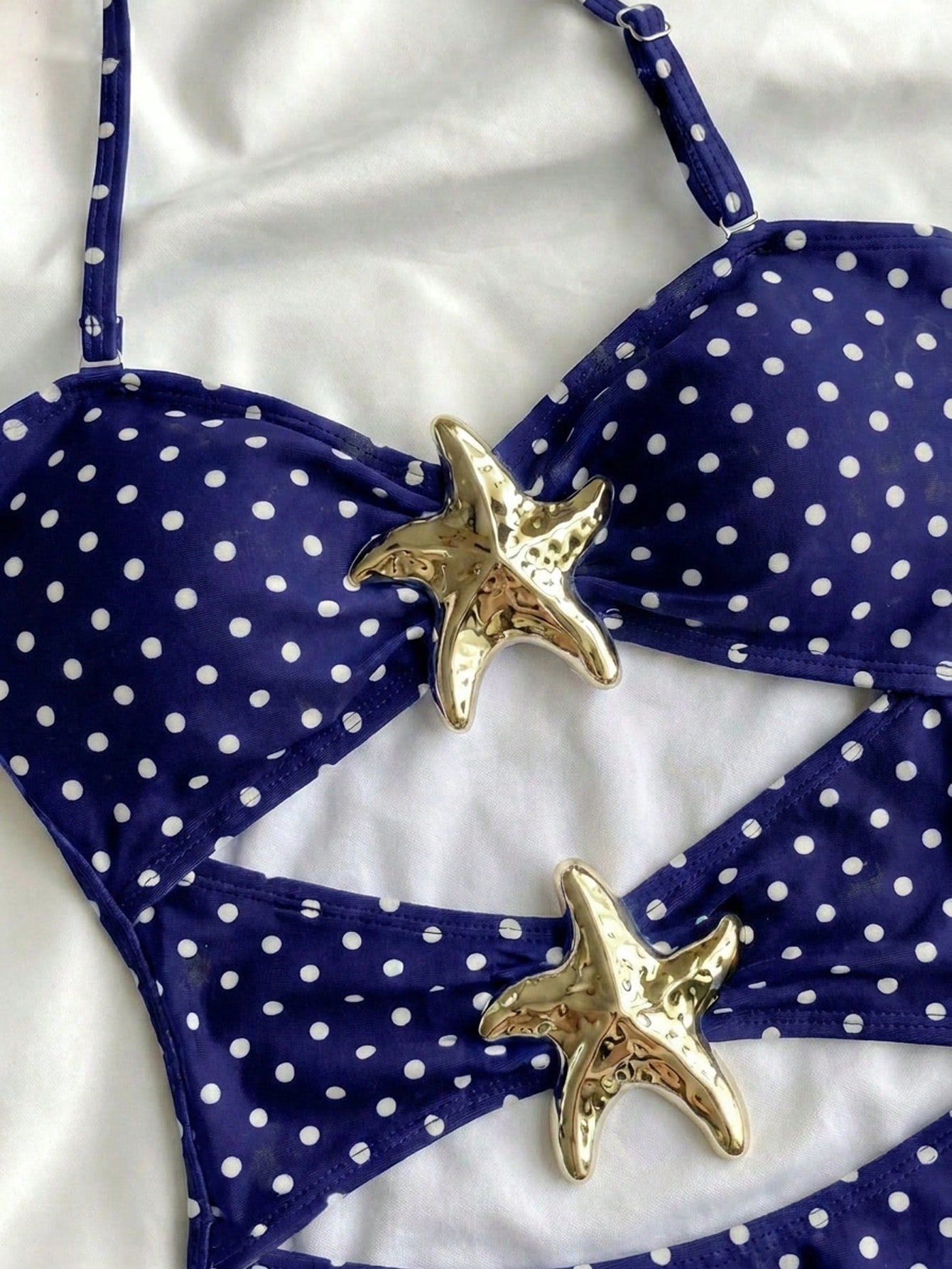 Tween girls' blue polka dot one-piece swimsuit with spaghetti strap halter neckline, high-cut bottom, and metal starfish decor for beach vacation wear.