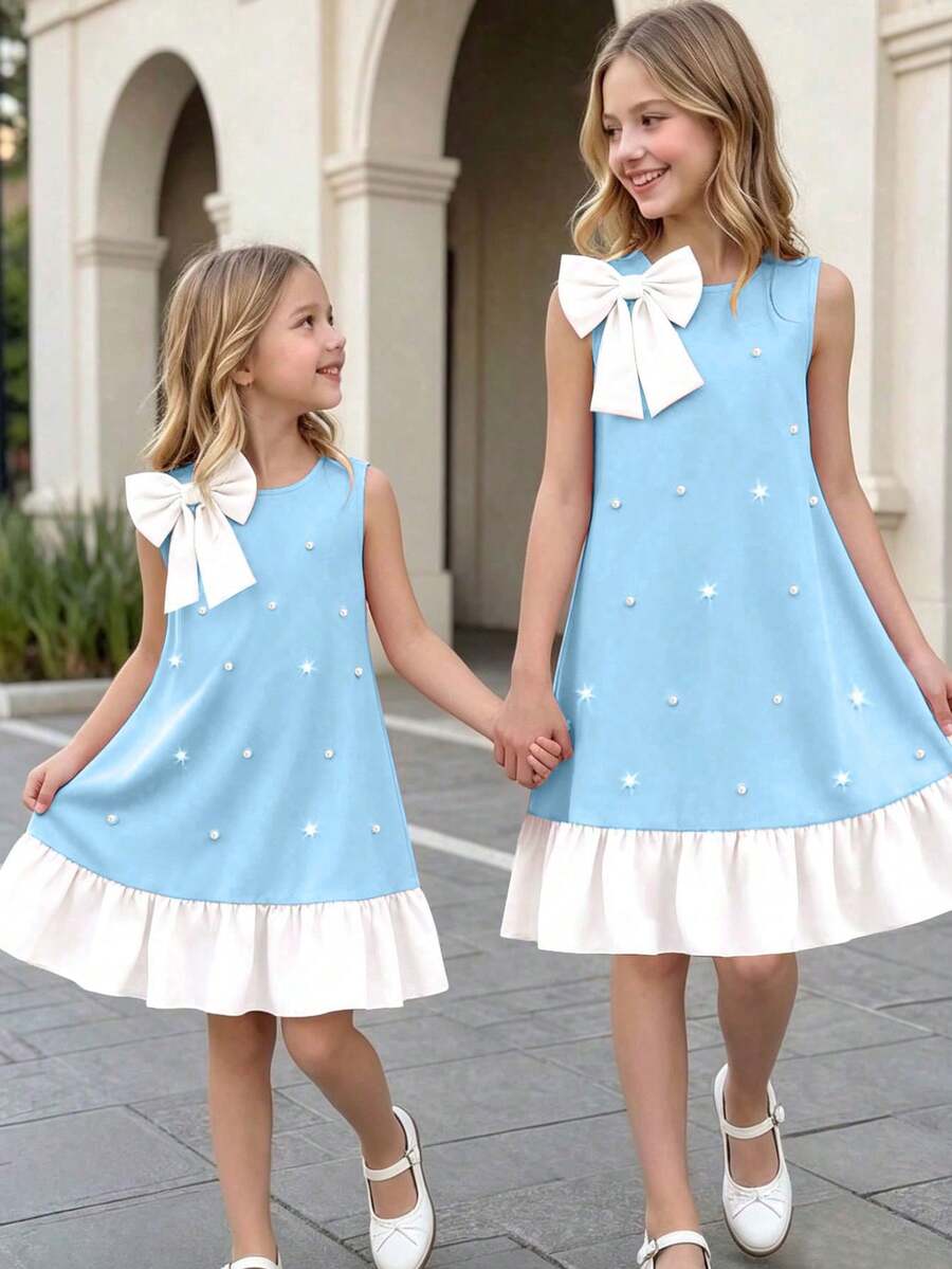 Yellow sleeveless colorblock dress for girls featuring a round neck, ruffle hem, and front bow detail.