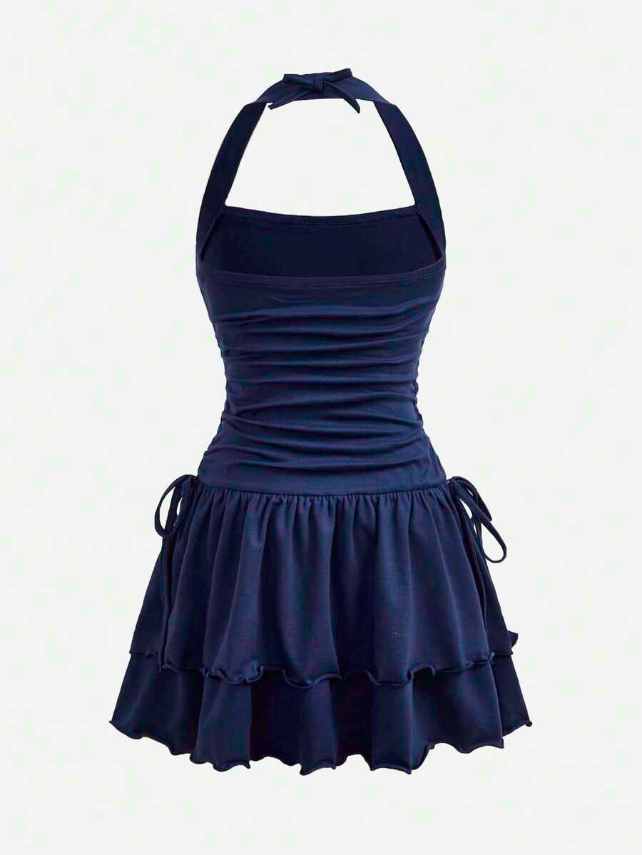 Tween girl wearing a black and white polka dot tiered cami dress with shoulder straps, a high waist, and a ruffle layered hem.