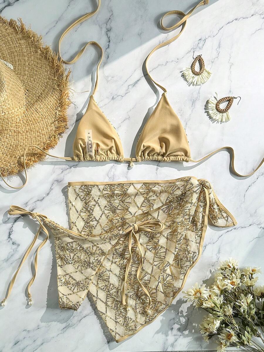 Women's 3-piece blue tropical shell print bikini set featuring a halter bralette top, low-waist tie-side bottom, and a matching sheer mesh cover-up skirt.