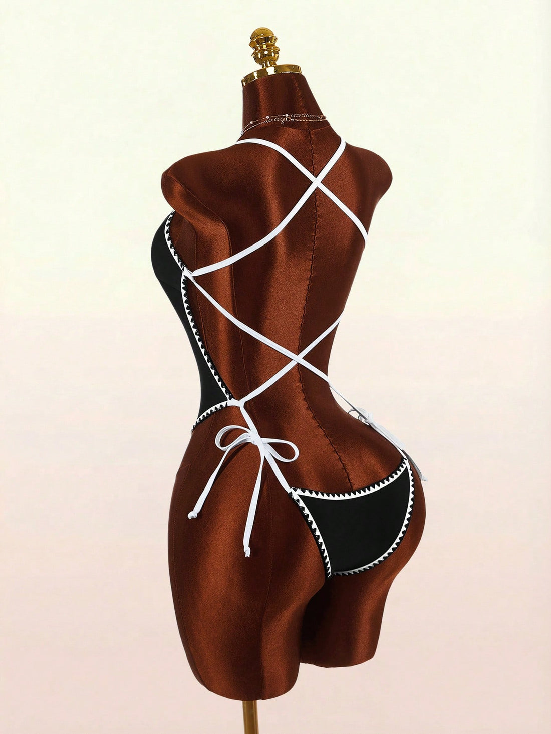 Women's backless colorblock one-piece swimsuit in black and white with criss-cross spaghetti straps, knot detail, and high cut bottom.
