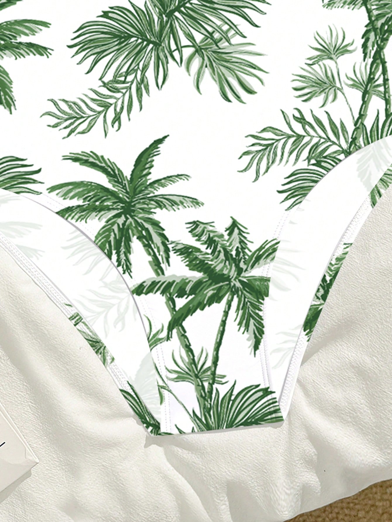 Tween girls one-piece swimsuit with a black base and multicolor tropical plant print featuring bamboo, palm leaves, plumeria flowers, scoop neck, and wide straps.