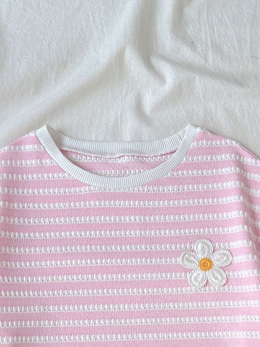 Tween girl wearing a black and white striped drop-shoulder crew neck t-shirt with bow embroidery paired with matching tie-waist shorts.