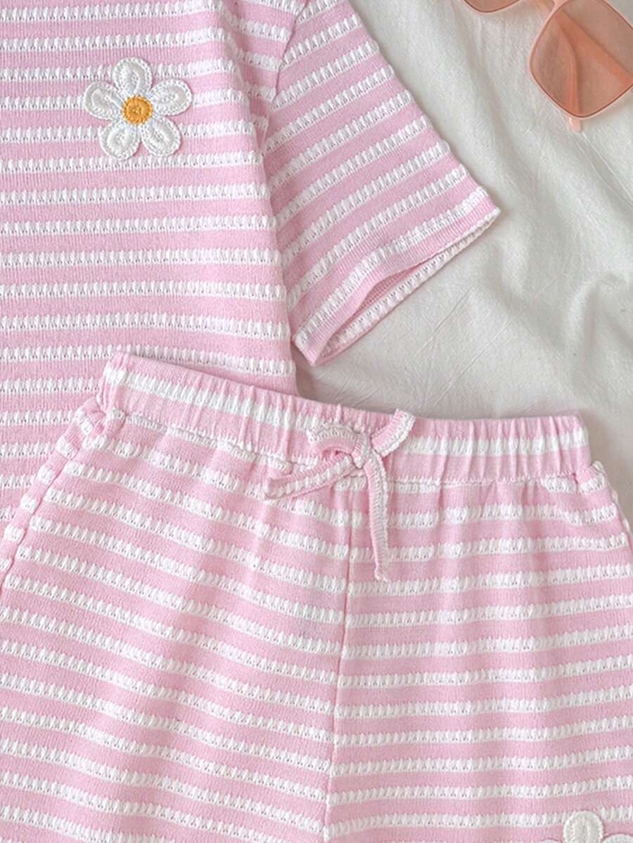 Tween girl wearing a black and white striped drop-shoulder crew neck t-shirt with bow embroidery paired with matching tie-waist shorts.