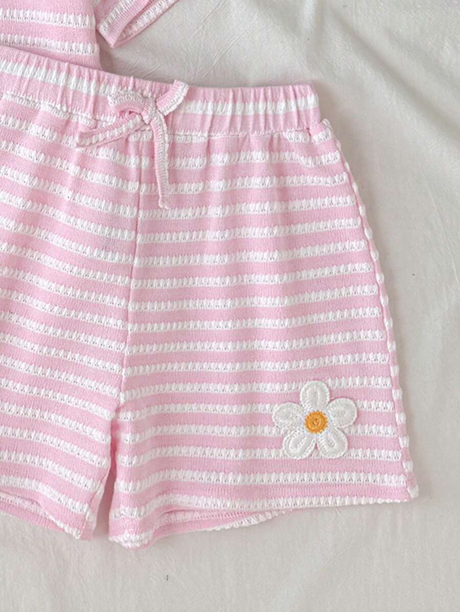 Tween girl wearing a black and white striped drop-shoulder crew neck t-shirt with bow embroidery paired with matching tie-waist shorts.