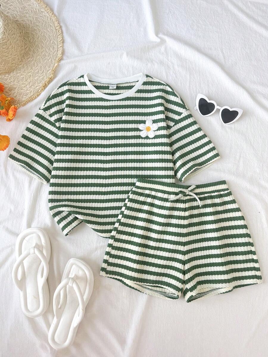 Tween girl wearing a black and white striped drop-shoulder crew neck t-shirt with bow embroidery paired with matching tie-waist shorts.