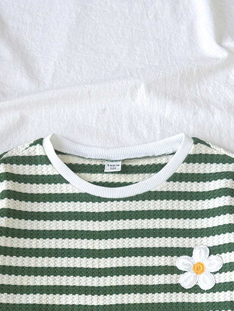 Tween girl wearing a black and white striped drop-shoulder crew neck t-shirt with bow embroidery paired with matching tie-waist shorts.