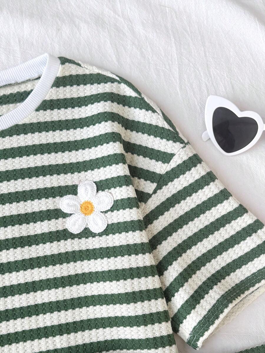 Tween girl wearing a black and white striped drop-shoulder crew neck t-shirt with bow embroidery paired with matching tie-waist shorts.