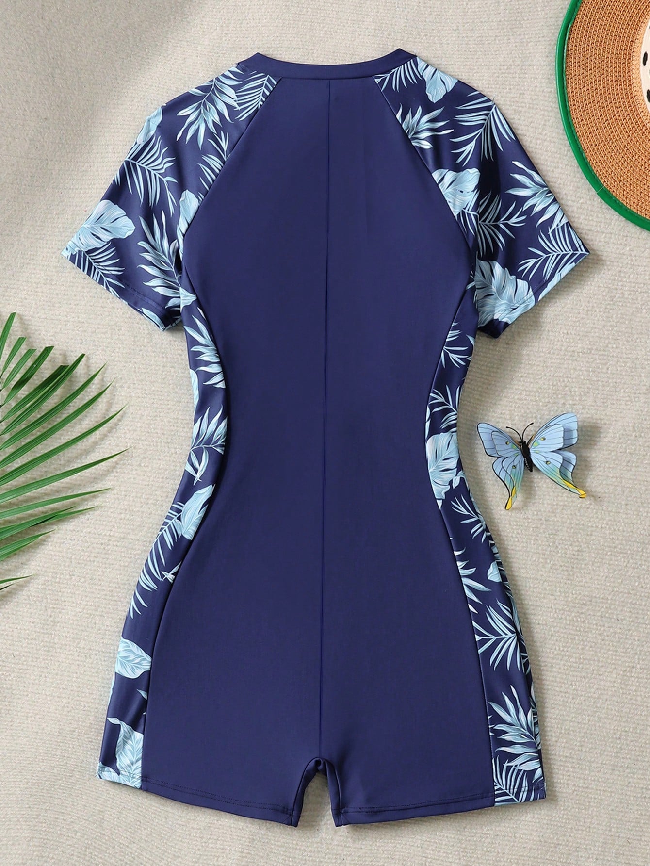 Black and white one-piece rashguard swimsuit for tween girls with short sleeves, high neck, zipper detail, fitted shape, and shorts-style bottom.