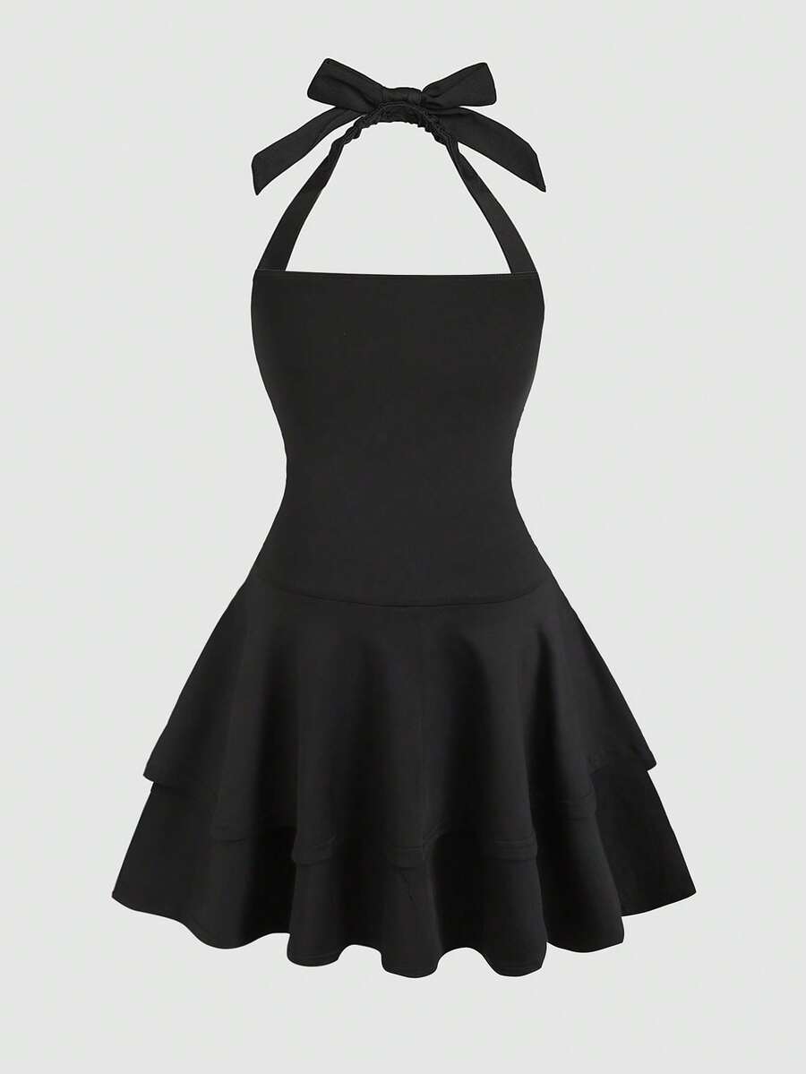 Black sleeveless halter polka dot mini dress for tween girls featuring a high waist and flared hem