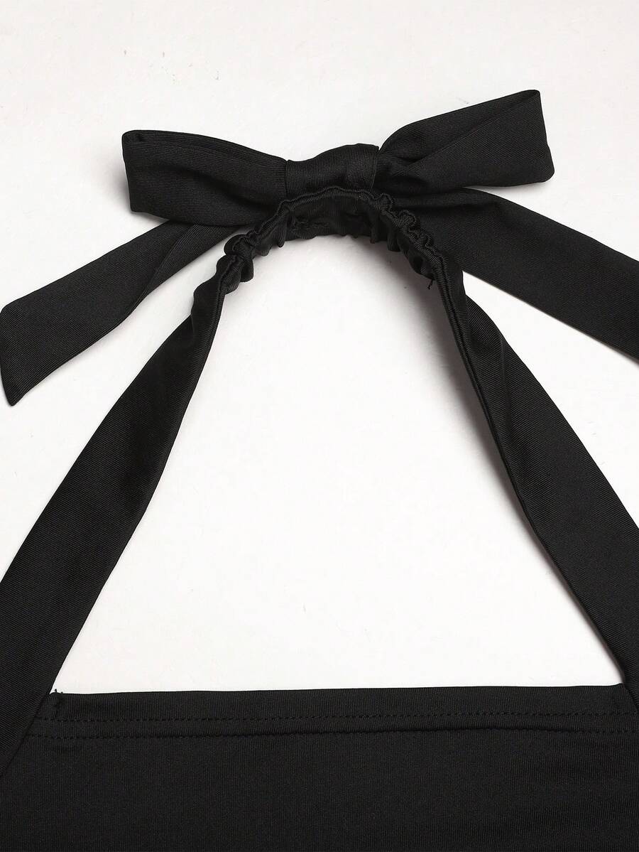 Black sleeveless halter polka dot mini dress for tween girls featuring a high waist and flared hem