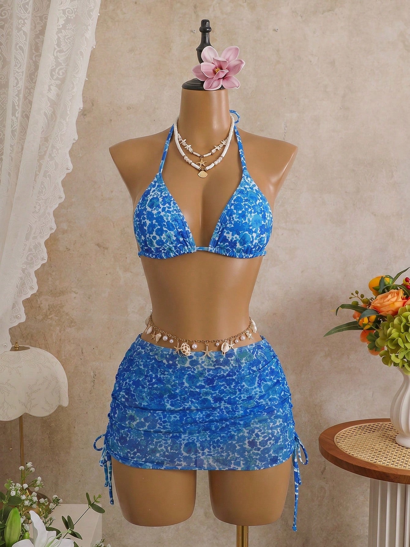 Women's black 3-piece bikini set featuring a halter triangle top with removable padding, high-waisted bottoms, and a knee-length mesh skirt with tie details.